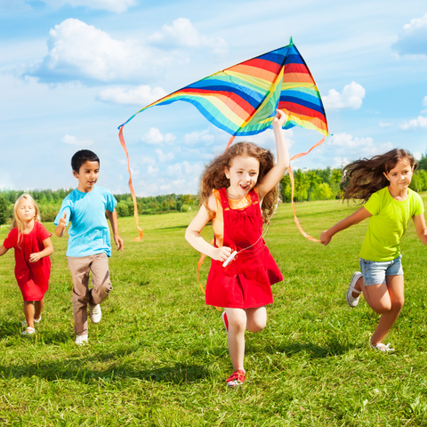 kids playing in the park camp outdoors grass green fun making a kite 